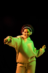 Image showing African-american woman\'s portrait isolated on dark studio background in orange-green neon light