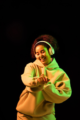 Image showing African-american woman\'s portrait isolated on dark studio background in orange-green neon light