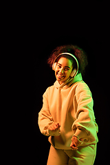 Image showing African-american woman\'s portrait isolated on dark studio background in orange-green neon light