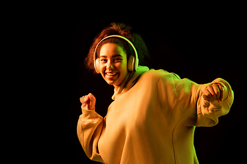 Image showing African-american woman\'s portrait isolated on dark studio background in orange-green neon light