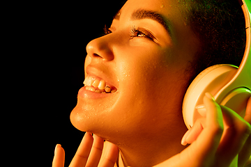 Image showing African-american woman\'s portrait isolated on dark studio background in orange-green neon light