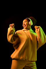 Image showing African-american woman\'s portrait isolated on dark studio background in orange-green neon light