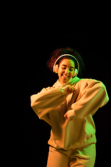 Image showing African-american woman\'s portrait isolated on dark studio background in orange-green neon light