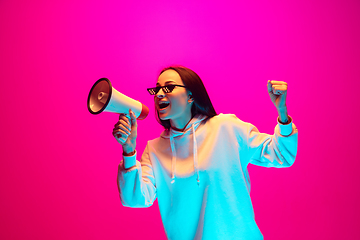 Image showing Caucasian beautiful woman\'s portrait isolated on pink studio background in multicolored neon light