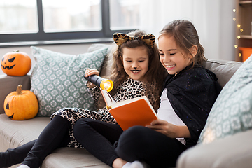 Image showing girls in halloween costumes reading book at home