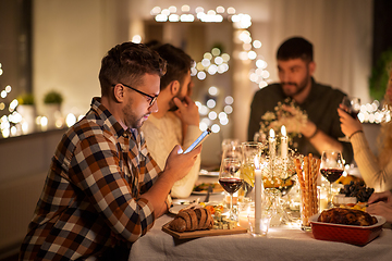 Image showing man with smartphone at dinner party with friends