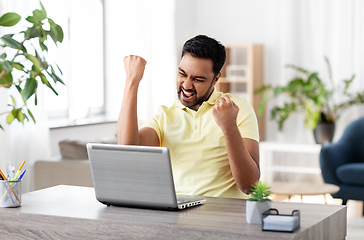 Image showing happy man with laptop working at home office