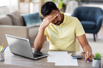 Image showing man with calculator and papers working at home