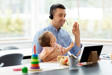 Image showing father in headset working at home office with baby