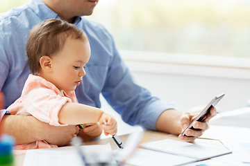 Image showing father with baby and smartphone working at home