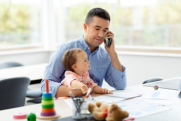 Image showing father with baby calling on phone at home office