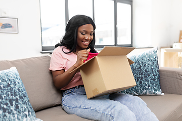 Image showing african american woman opening parcel box at home