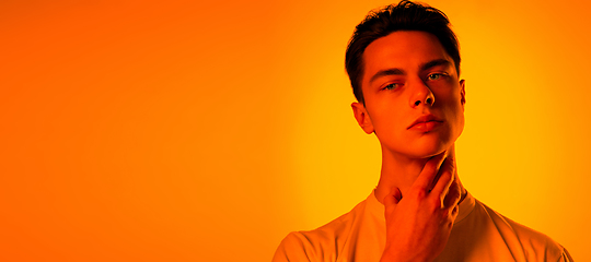 Image showing Handsome caucasian man\'s portrait isolated on orange studio background in neon light, monochrome