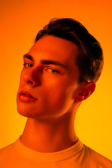 Image showing Handsome caucasian man\'s portrait isolated on orange studio background in neon light, monochrome