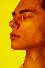 Image showing Handsome caucasian man\'s portrait isolated on orange studio background in neon light, monochrome