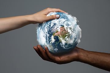 Image showing Two hands holding planet Earth, close up. Environment save, taking care of nature and ecology, supporting hands concept