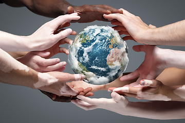 Image showing Hands holding planet Earth, close up on grey background. Environment save, taking care of nature and ecology, supporting hands concept