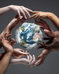 Image showing Hands holding planet Earth, close up on grey background. Environment save, taking care of nature and ecology, supporting hands concept