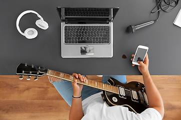 Image showing young man with guitar and smartphone at table