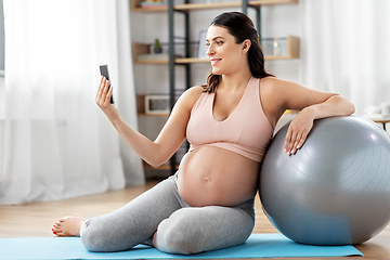 Image showing pregnant woman with phone and fitness ball at home