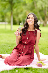 Image showing happy woman with drink in bottle at picnic in park