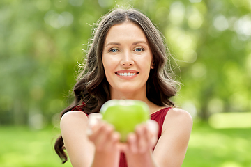 Image showing happy woman eating green apple at summer park