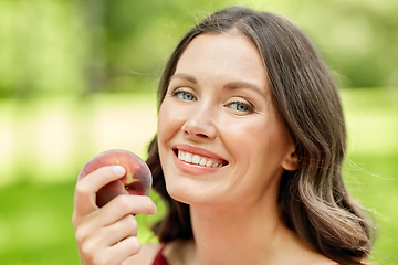 Image showing happy woman eating peach at summer park