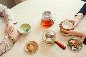 Image showing Close up female hands pouring tea in cup at restaurant or cafe, daily lifestyle