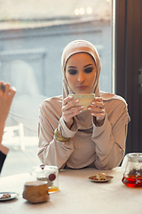 Image showing Beautiful arab woman meeting at cafe or restaurant with friend, spending time with cup of tea