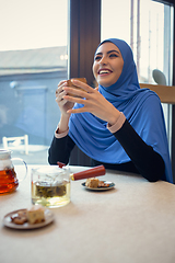 Image showing Beautiful arab woman meeting at cafe or restaurant with friend, spending time with cup of tea