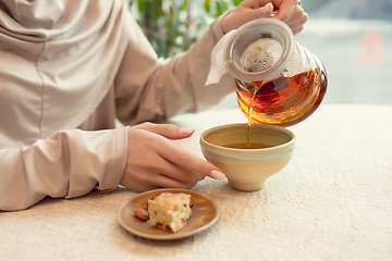 Image showing Close up female hands pouring tea in cup at restaurant or cafe, daily lifestyle