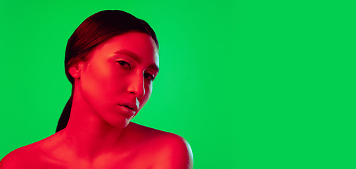 Image showing Beautiful east woman close up portrait isolated on green background in red neon light