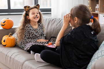 Image showing girls in halloween costumes with candies at home