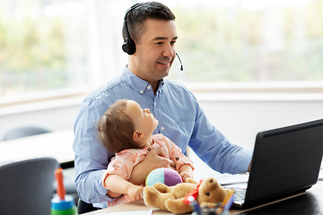 Image showing father with baby working on laptop at home office