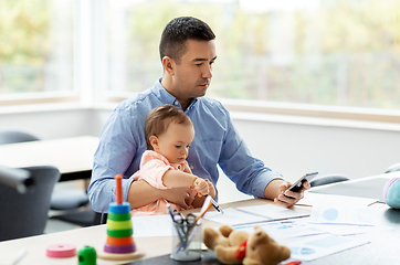 Image showing father with baby and smartphone working at home