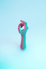 Image showing Close up female hand gesturing from the milk bath with soft glowing in neon light