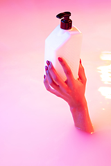 Image showing Close up female hand gesturing from the milk bath with soft glowing in neon light