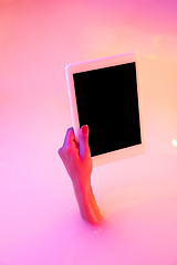 Image showing Close up female hand gesturing from the milk bath with soft glowing in neon light