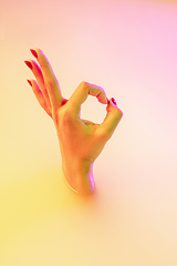 Image showing Close up female hand gesturing from the milk bath with soft glowing in neon light