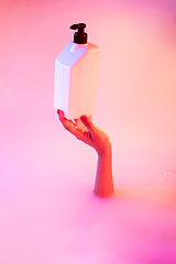 Image showing Close up female hand gesturing from the milk bath with soft glowing in neon light