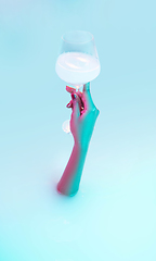 Image showing Close up female hand gesturing from the milk bath with soft glowing in neon light