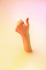 Image showing Close up female hand gesturing from the milk bath with soft glowing in neon light