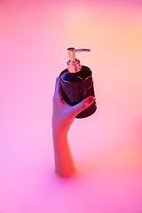 Image showing Close up female hand gesturing from the milk bath with soft glowing in neon light