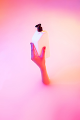 Image showing Close up female hand gesturing from the milk bath with soft glowing in neon light