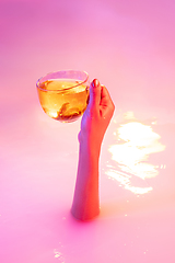 Image showing Close up female hand gesturing from the milk bath with soft glowing in neon light