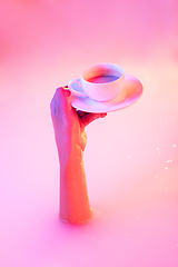 Image showing Close up female hand gesturing from the milk bath with soft glowing in neon light