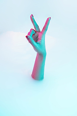 Image showing Close up female hand gesturing from the milk bath with soft glowing in neon light