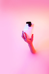 Image showing Close up female hand gesturing from the milk bath with soft glowing in neon light