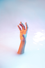 Image showing Close up female hand gesturing from the milk bath with soft glowing in neon light