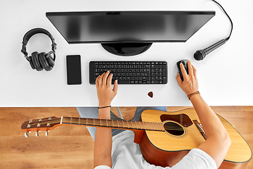 Image showing young man with computer and guitar at table